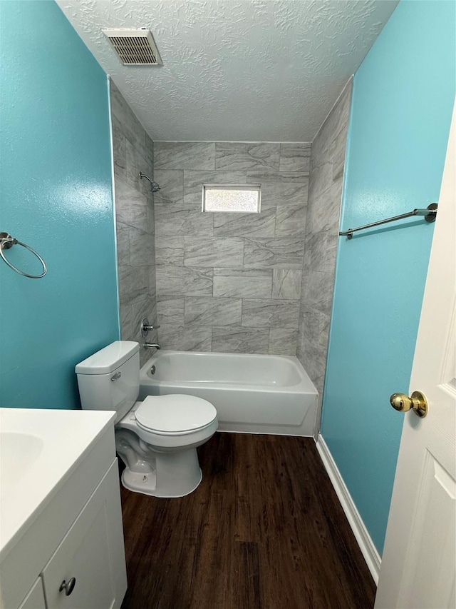 full bathroom featuring toilet, a textured ceiling, vanity, hardwood / wood-style floors, and tiled shower / bath combo