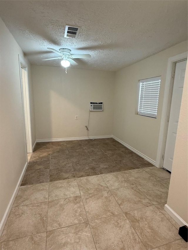 spare room with a textured ceiling, a wall mounted AC, and ceiling fan