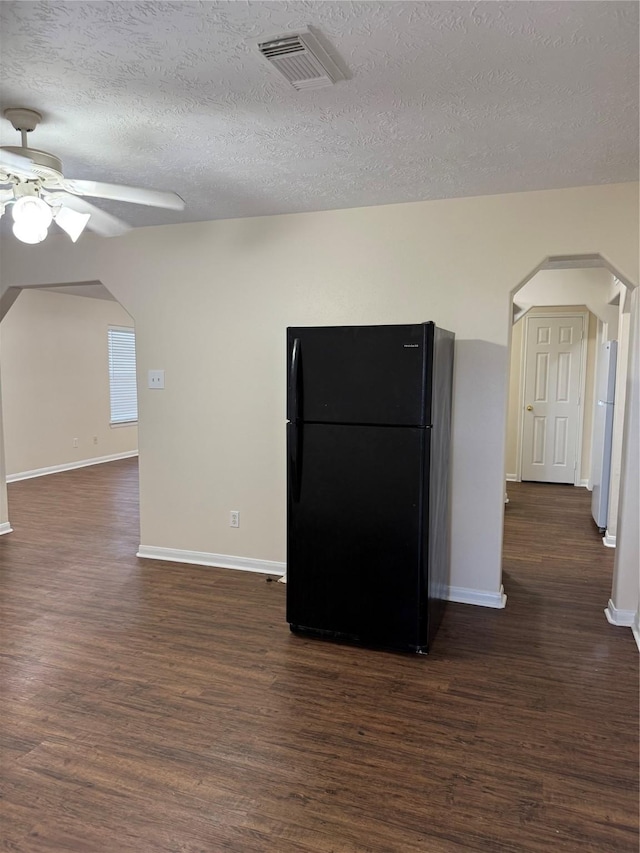 kitchen featuring a textured ceiling, ceiling fan, black fridge, and dark hardwood / wood-style floors