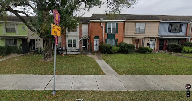 view of property with brick siding and a front lawn