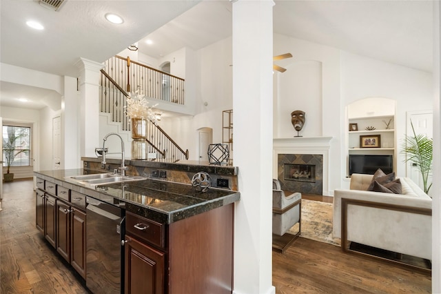 kitchen featuring sink, stainless steel dishwasher, a tile fireplace, and dark hardwood / wood-style floors