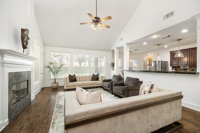 living room with dark hardwood / wood-style flooring, high vaulted ceiling, ornate columns, and ceiling fan