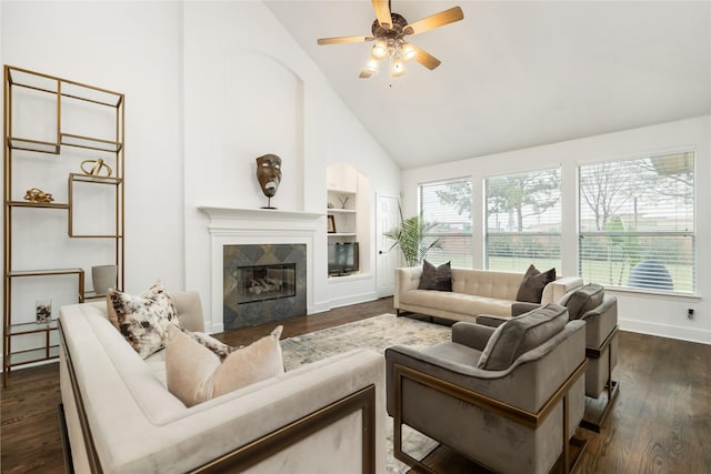 living room with dark wood-type flooring, a high end fireplace, built in shelves, and plenty of natural light