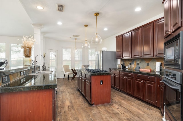 kitchen with sink, a kitchen island, decorative light fixtures, black microwave, and wall oven