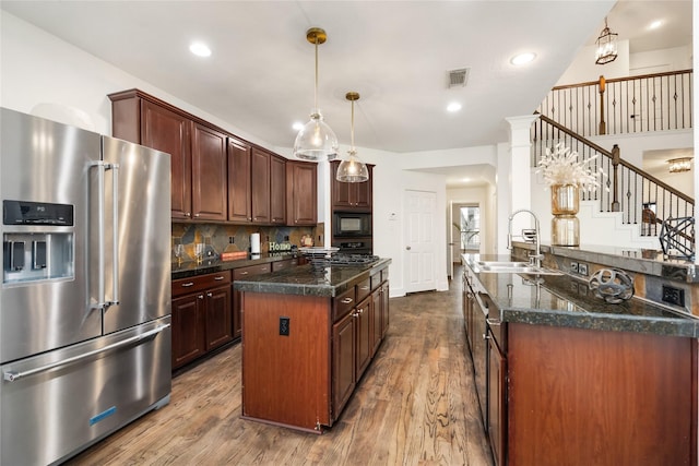 kitchen with dark brown cabinetry, high end refrigerator, sink, black microwave, and decorative backsplash