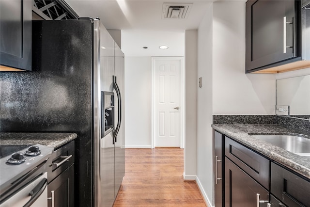 kitchen with light hardwood / wood-style floors, stainless steel fridge with ice dispenser, and dark stone countertops