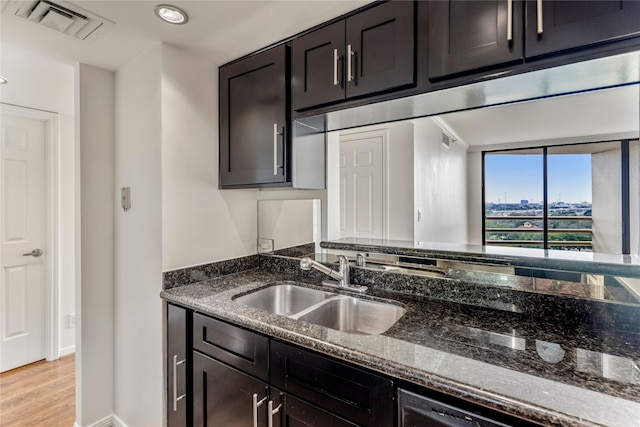 kitchen with dark brown cabinetry, light hardwood / wood-style floors, sink, and dark stone counters