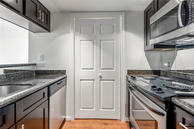 kitchen featuring sink, light hardwood / wood-style floors, stainless steel appliances, and dark stone countertops