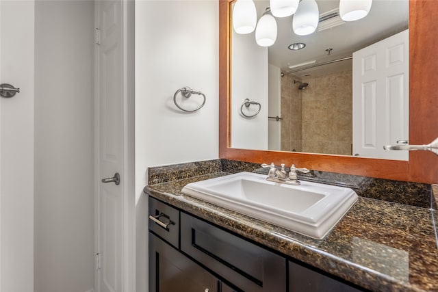 bathroom with tiled shower and vanity