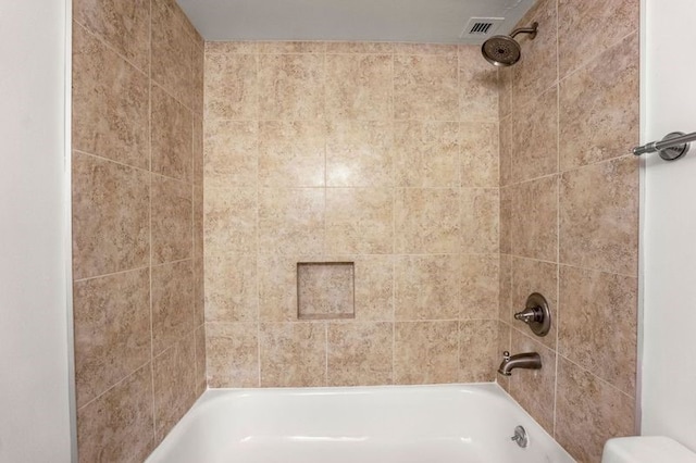 bathroom with toilet and tiled shower / bath