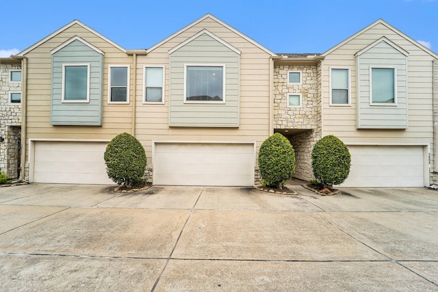 view of property with an attached garage, stone siding, and concrete driveway