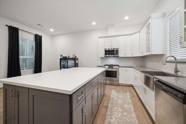 kitchen featuring sink, white cabinetry, a kitchen island, light hardwood / wood-style floors, and stainless steel appliances