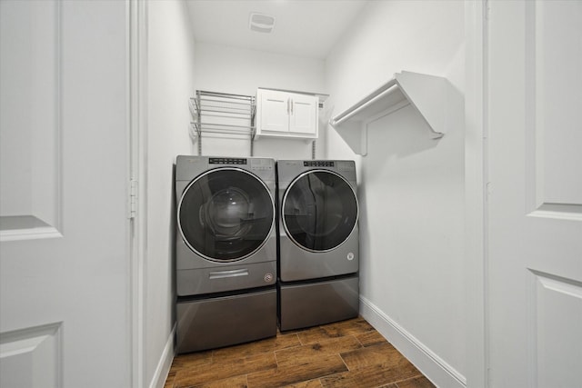 laundry room with cabinets, dark wood-type flooring, and washing machine and clothes dryer