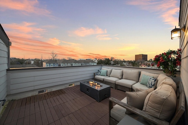 deck at dusk with an outdoor living space with a fire pit