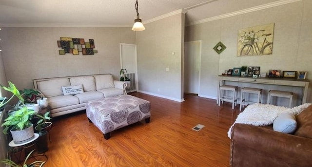 living area featuring visible vents, crown molding, baseboards, and wood finished floors