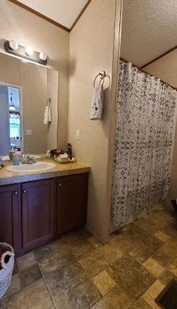 full bath featuring crown molding, stone finish floor, vanity, and a shower with curtain