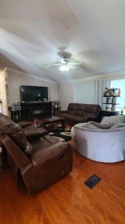 living room featuring a ceiling fan, lofted ceiling, wood finished floors, crown molding, and a textured ceiling