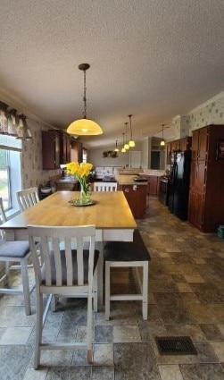 unfurnished dining area with stone finish flooring, visible vents, a textured ceiling, and wallpapered walls