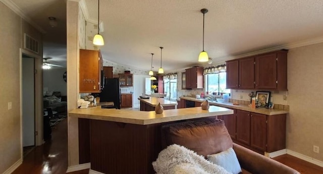 kitchen featuring lofted ceiling, a peninsula, dark wood-style flooring, light countertops, and ornamental molding