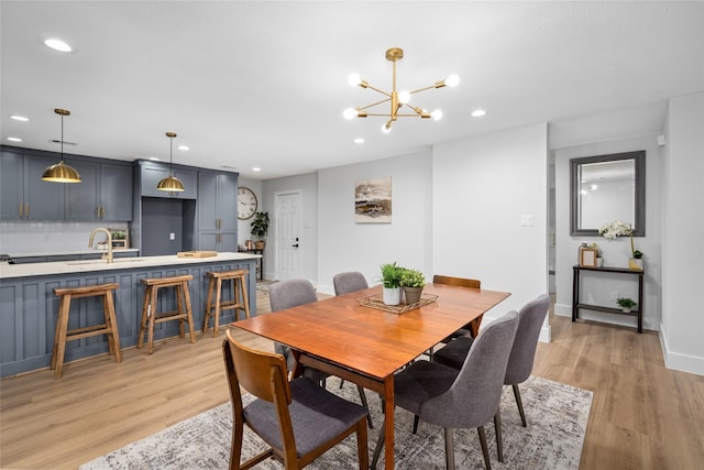 dining space featuring a notable chandelier, light hardwood / wood-style flooring, and sink