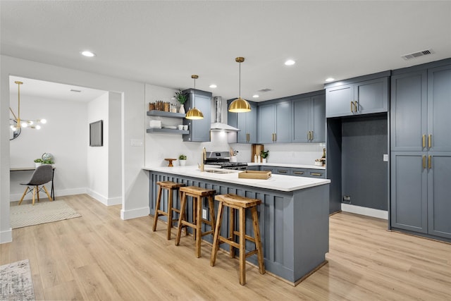 kitchen featuring a breakfast bar, light wood-type flooring, pendant lighting, stainless steel range, and kitchen peninsula