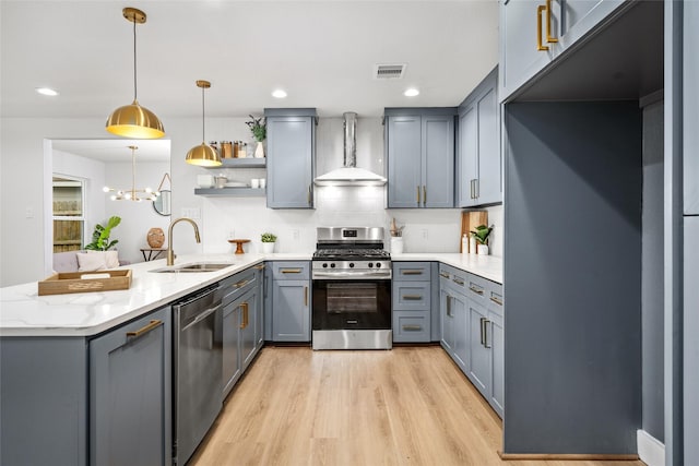 kitchen with light hardwood / wood-style flooring, sink, pendant lighting, stainless steel appliances, and wall chimney exhaust hood