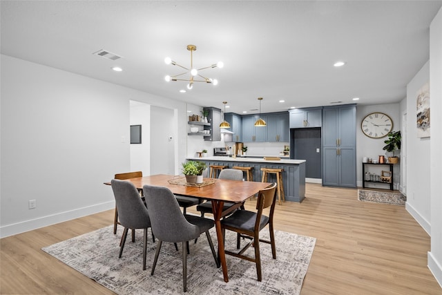 dining room with light wood-type flooring and an inviting chandelier