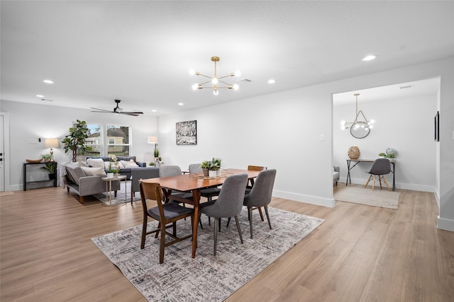 dining space with light hardwood / wood-style floors and ceiling fan with notable chandelier