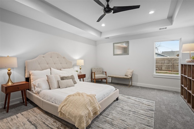 carpeted bedroom featuring ceiling fan and a raised ceiling