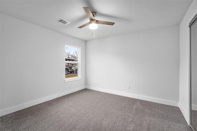 empty room with dark colored carpet and ceiling fan