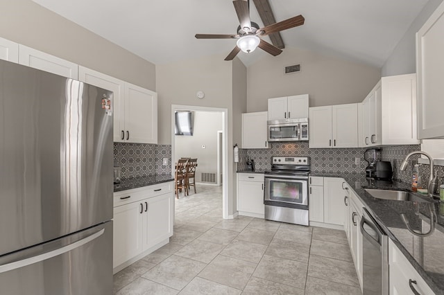 kitchen featuring stainless steel appliances, white cabinets, decorative backsplash, sink, and dark stone countertops