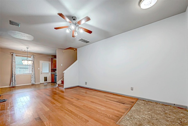 spare room featuring ceiling fan with notable chandelier and light hardwood / wood-style flooring