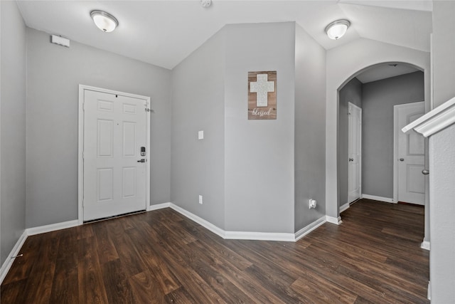 foyer entrance with dark wood-style floors, arched walkways, lofted ceiling, and baseboards