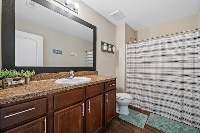 full bath with toilet, visible vents, wood finished floors, and vanity