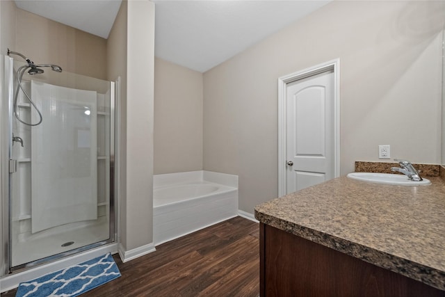 full bath with a garden tub, vanity, a shower stall, wood finished floors, and baseboards