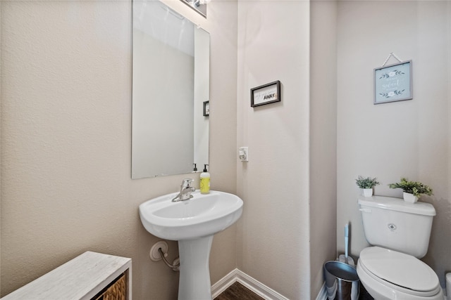 half bathroom with toilet and baseboards