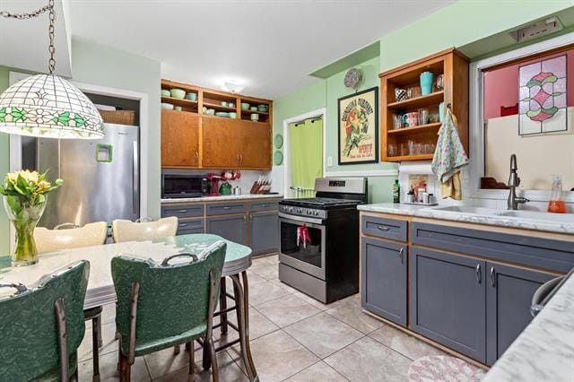 kitchen with appliances with stainless steel finishes, sink, light tile patterned floors, gray cabinetry, and decorative light fixtures