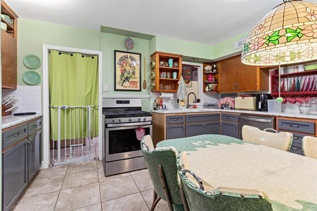 kitchen featuring appliances with stainless steel finishes, sink, backsplash, light tile patterned flooring, and gray cabinetry