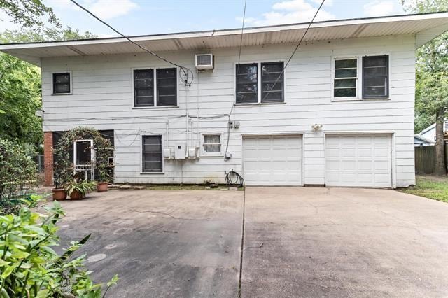 back of house with a garage and a wall mounted air conditioner