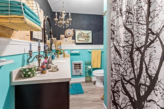 bathroom featuring hardwood / wood-style flooring, vanity, a chandelier, and toilet