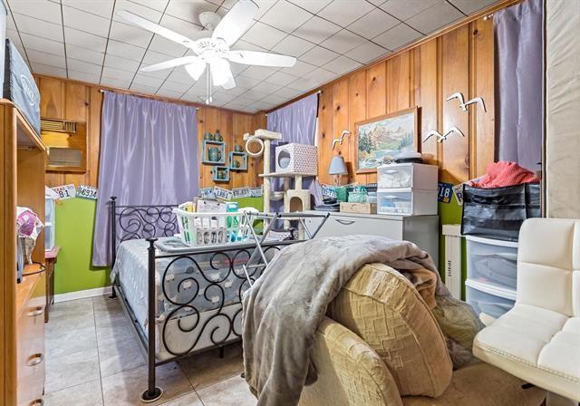 bedroom with light tile patterned floors and wood walls