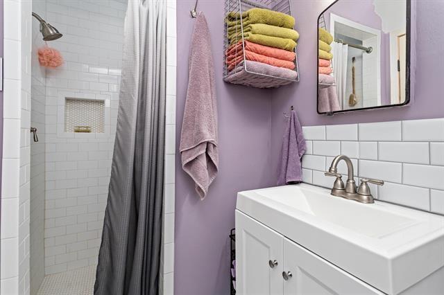 bathroom featuring decorative backsplash, vanity, and a shower with curtain