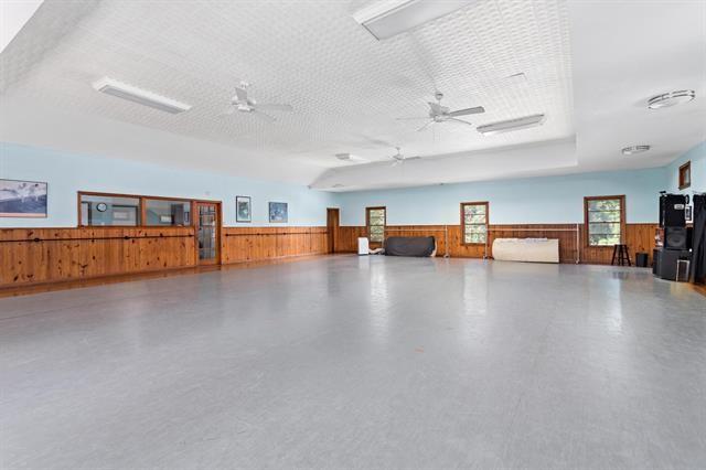 miscellaneous room featuring ceiling fan, wood walls, and a textured ceiling