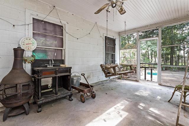 sunroom / solarium with ceiling fan, sink, and a wood stove