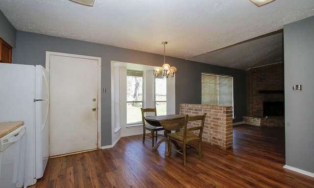 dining space with a notable chandelier, dark wood-type flooring, a textured ceiling, lofted ceiling, and a brick fireplace