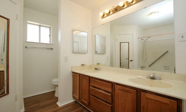 bathroom with hardwood / wood-style flooring, toilet, vanity, and a shower