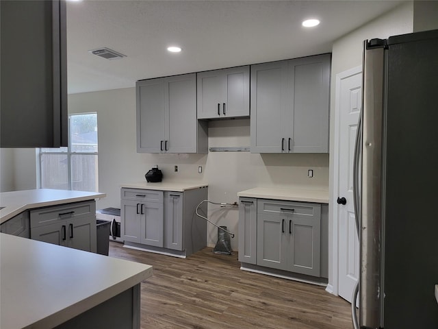 kitchen with dark wood-type flooring, gray cabinetry, and stainless steel fridge