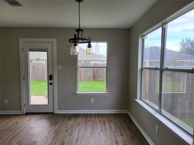 unfurnished dining area featuring hardwood / wood-style flooring and a notable chandelier