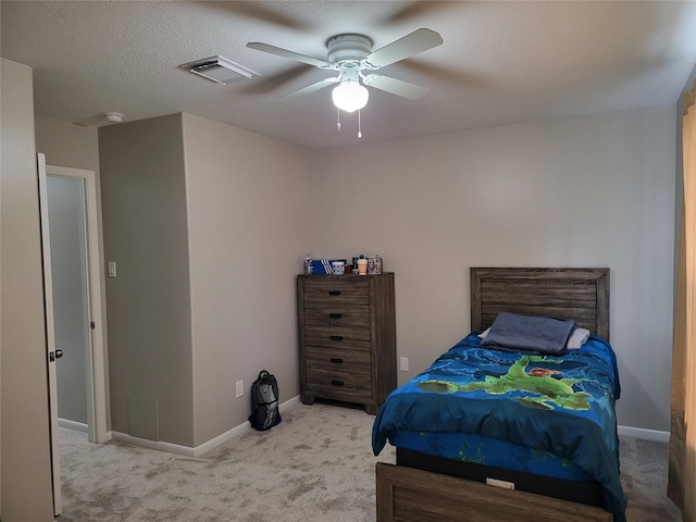 bedroom featuring ceiling fan, light carpet, and a textured ceiling