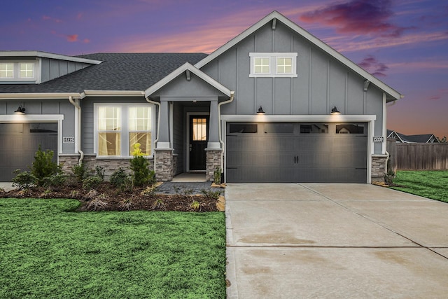 view of front facade featuring concrete driveway, board and batten siding, a garage, stone siding, and a front lawn